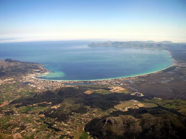 Luchtfoto van de Badia d'Alcúdia met het lange Playa de Alcúdia strand en de bergen op de achtergrond