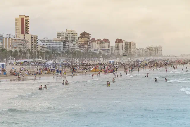 Het brede zandstrand Platja de Gandia met de boulevard erachter Het brede zandstrand Platja de Gandia met de boulevard erachter