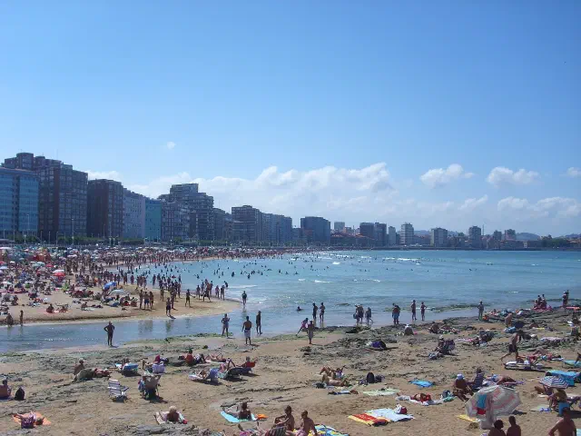 Drukke zomerdag op het stadsstrand Playa de San Lorenzo in Gijón bij de monding van de Piles Drukke zomerdag op het stadsstrand Playa de San Lorenzo in Gijón bij de monding van de Piles