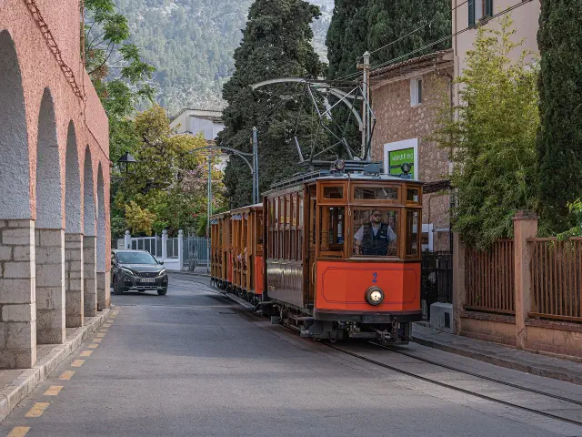 De oranje tram van Sóller rijdt over straat tussen het stadje en de Port de Sóller De oranje tram van Sóller rijdt over straat tussen het stadje en de Port de Sóller